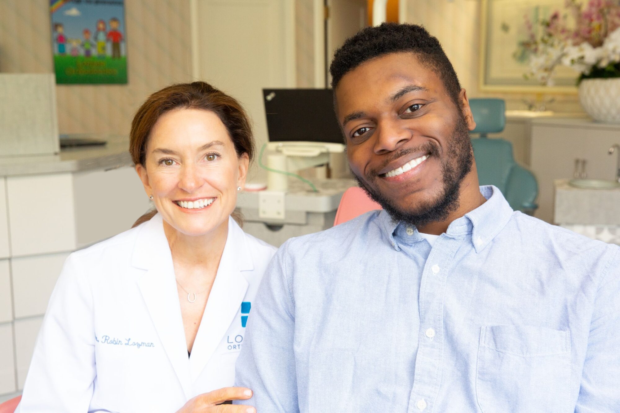 Smiling orthodontist in white coat with patient in dental chair, showcasing personalized care at Lozman Orthodontics, emphasizing orthodontic solutions like Invisalign for Loudonville and Meadowdale Estates.